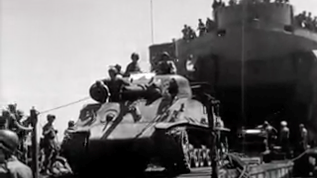 Zwart-wit beeld van een Sherman tank met Nederlandse militairen wordt vanuit het schip aan wal gereden ten tijden de eerste 'politionele actie'