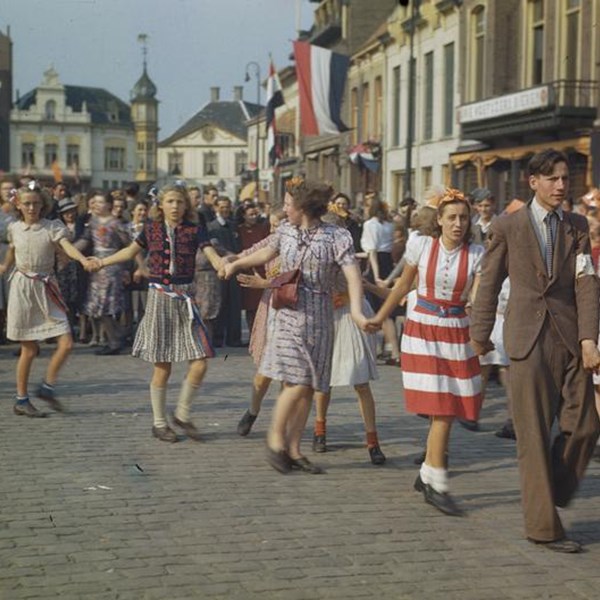 Foto van mensen die hand in hand door de straat gaan ten tijden van de bevrijding in 1945